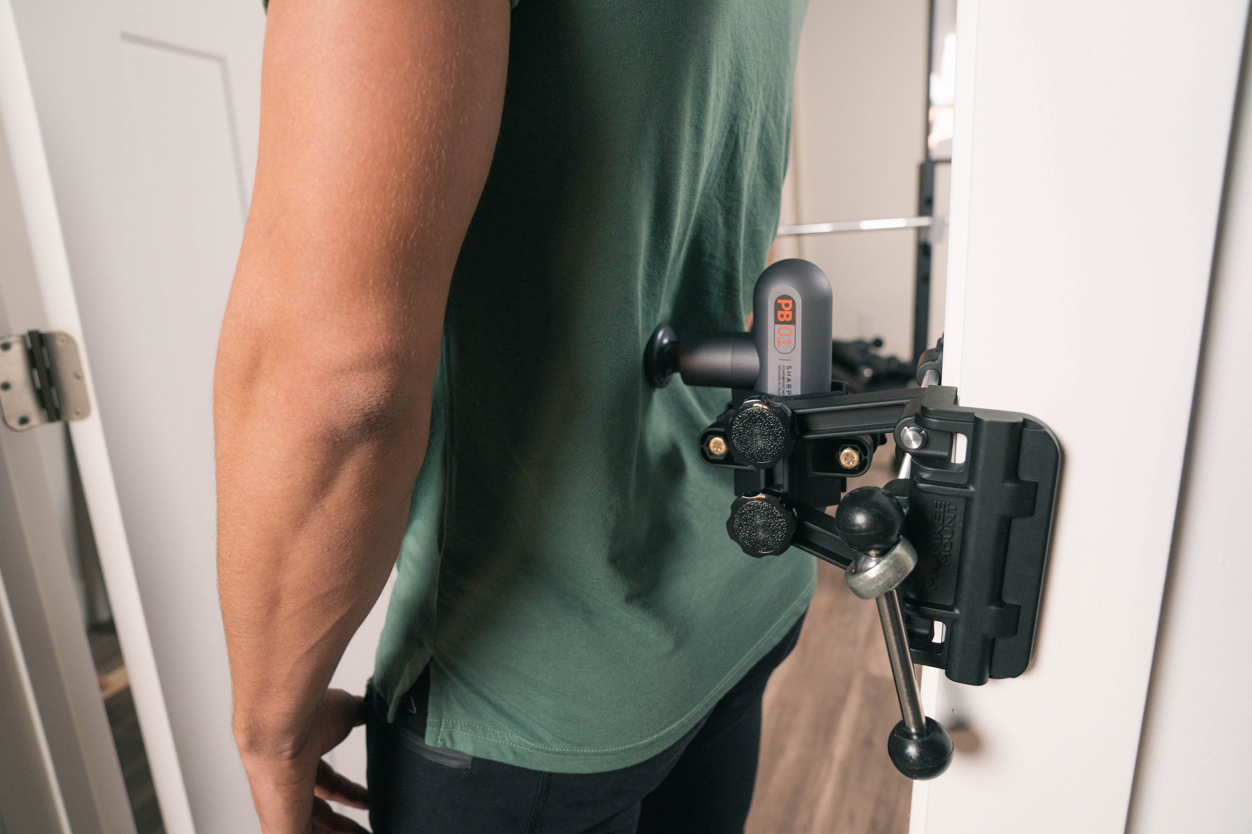 Person using mounted massage gun on their lower back